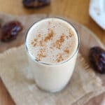 Tahini date smoothie in a glass surrounded by dates.