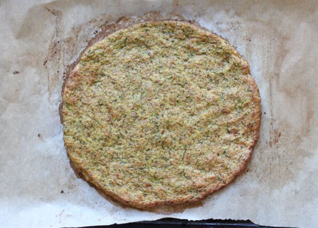 Baked zucchini pizza crust on a baking sheet.