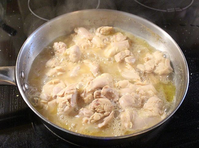 Chicken cooking in a steel pan.