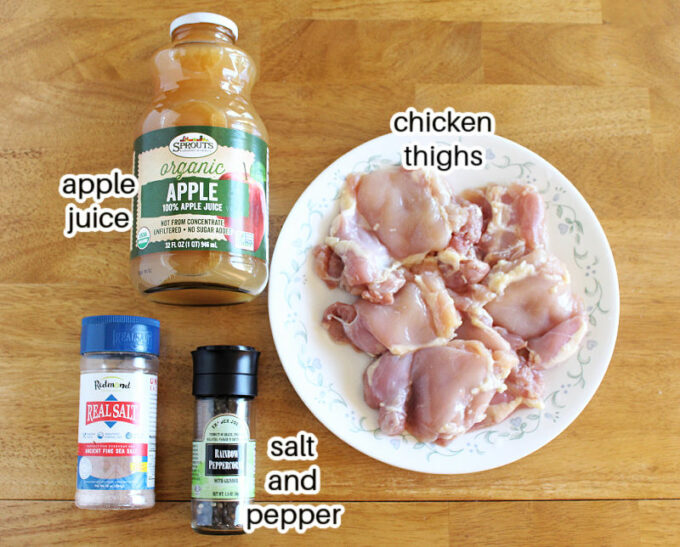 Chicken, apple juice, salt, and pepper laid out on a table.