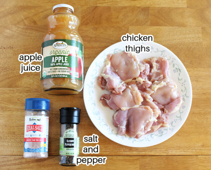 Chicken, apple juice, salt, and pepper laid out on a table.
