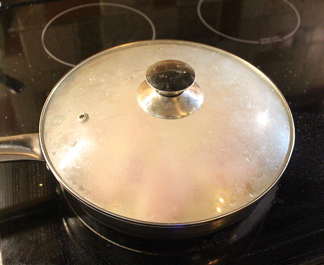 Covered pan on a black stove.