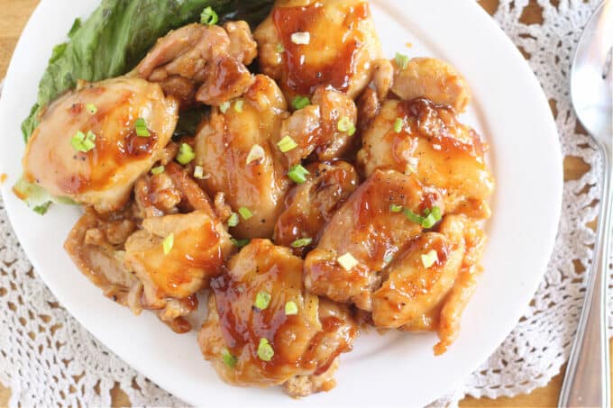 Overhead shot of a plateful of chicken thighs topped with a reddish-brown sauce.