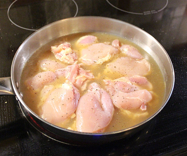 Chicken thighs in a pan on a black electric stove.