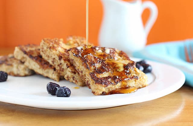 Slices of oatmeal French toast with maple syrup and blueberries on a plate.