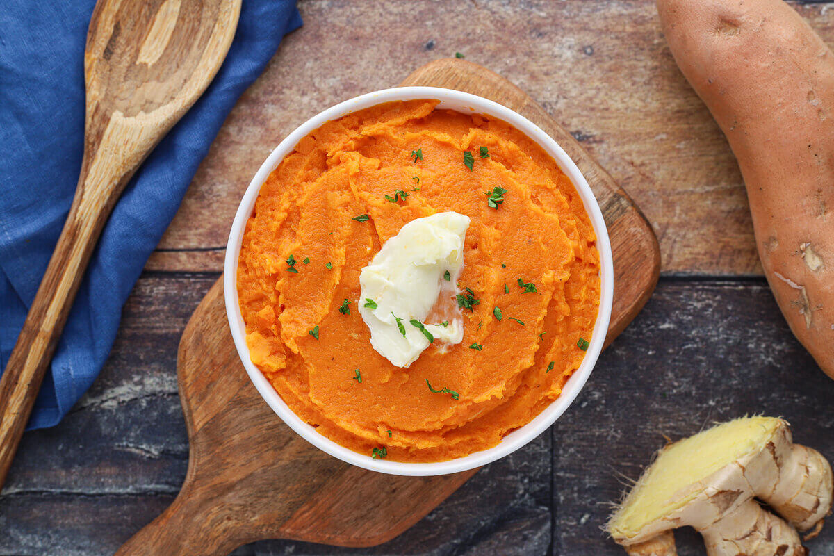 Mashed sweet potatoes topped with butter in a bowl.