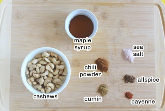 Cashews, spices, and maple syrup on a table.