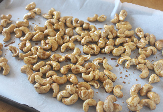Cashews spread out on a baking sheet.
