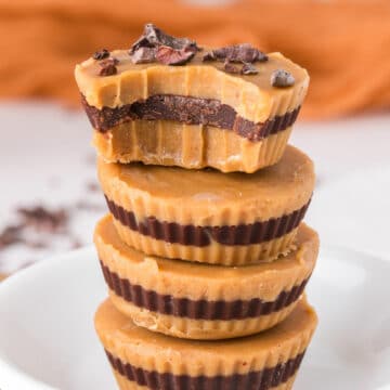 Stack of four peanut butter cups with cacao nibs on top.