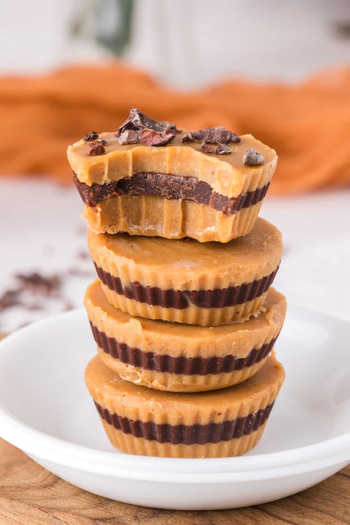 Stack of four peanut butter cups with cacao nibs on top.