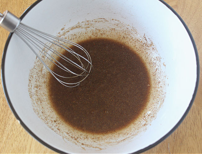 Bowl with maple syrup and spices being whisked.