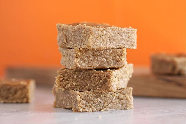 Almond butter bars with an orange background.