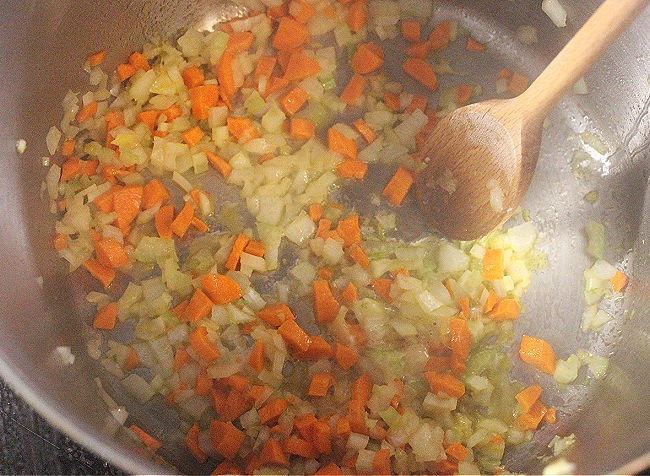 Sauteing vegetables in a large steel pot.