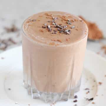 Chocolate smoothie in a glass on a white plate.