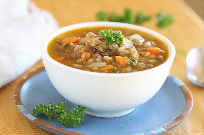 Lentil soup in a white bowl on a blue plate.