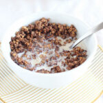 Chocolate granola in a bowl with a spoon.