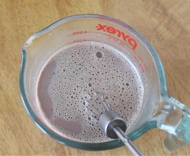 Foamy chocolate milk in a measuring pitcher.