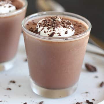 Chocolate pudding in a glass topped with whipped cream and chocolate.