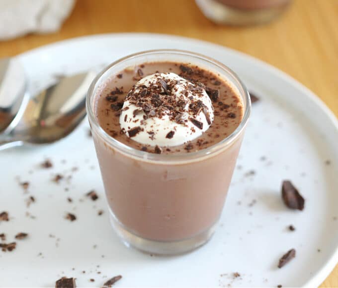 Chocolate pudding in a glass with whipped cream and chocolate shavings.