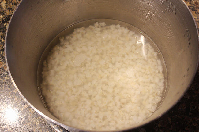 Cooked rice in water in a steel pot.