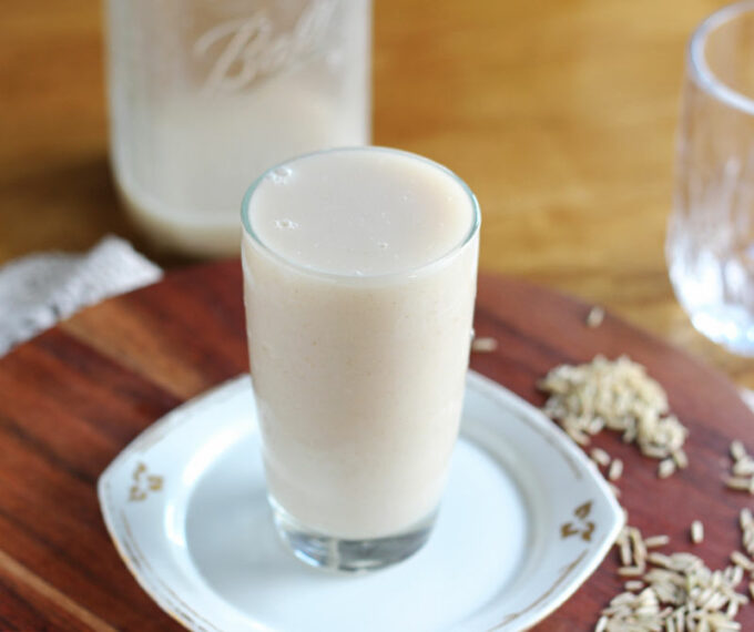 Glass of milk on a white plate with raw rice surrounding it.