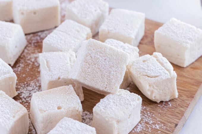 Pile of large marshmallows on a cutting board.