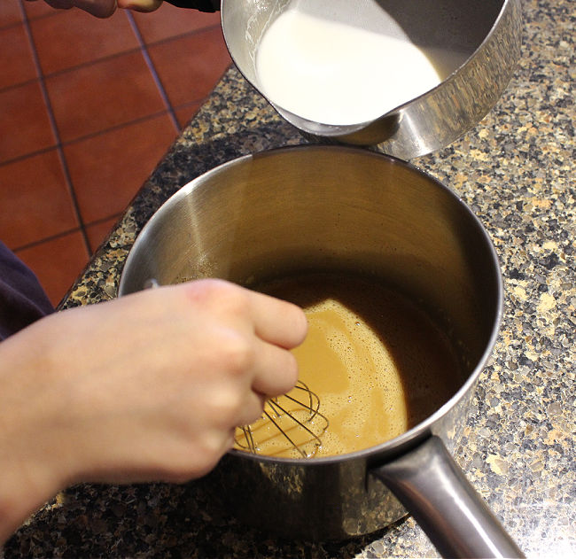 Milk being poured from one pot into another pot.