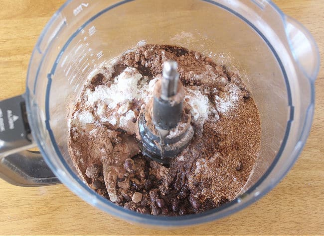 Beans, sugar, cocoa powder, and other various ingredients in a food processor.