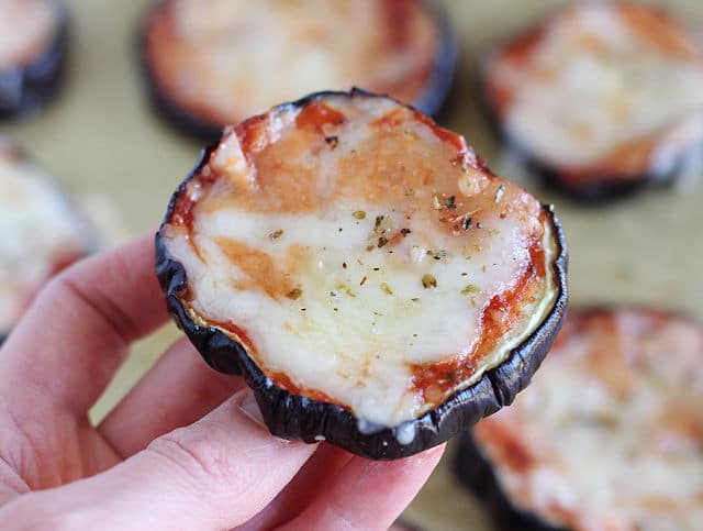 Hand holding low carb pizza made with an eggplant