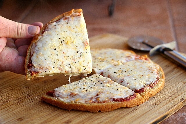 Quinoa pizza crust with cheese on a cutting board.