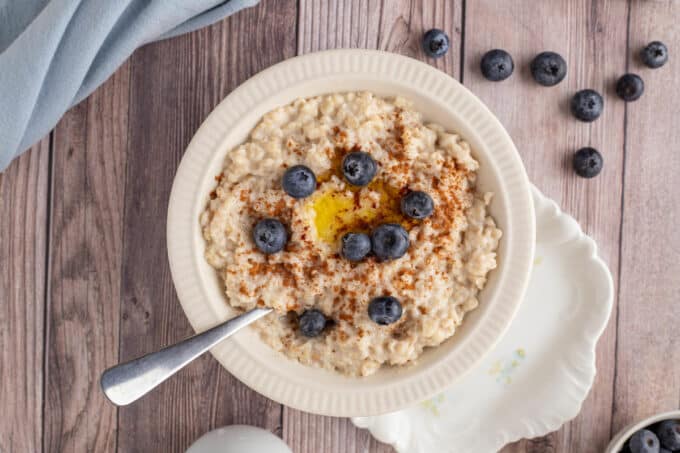 Bowl of oatmeal with butter and blueberries.