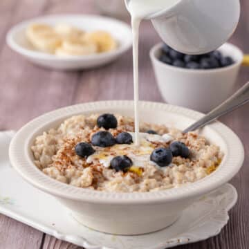 Pouring milk over a bowl of oatmeal.