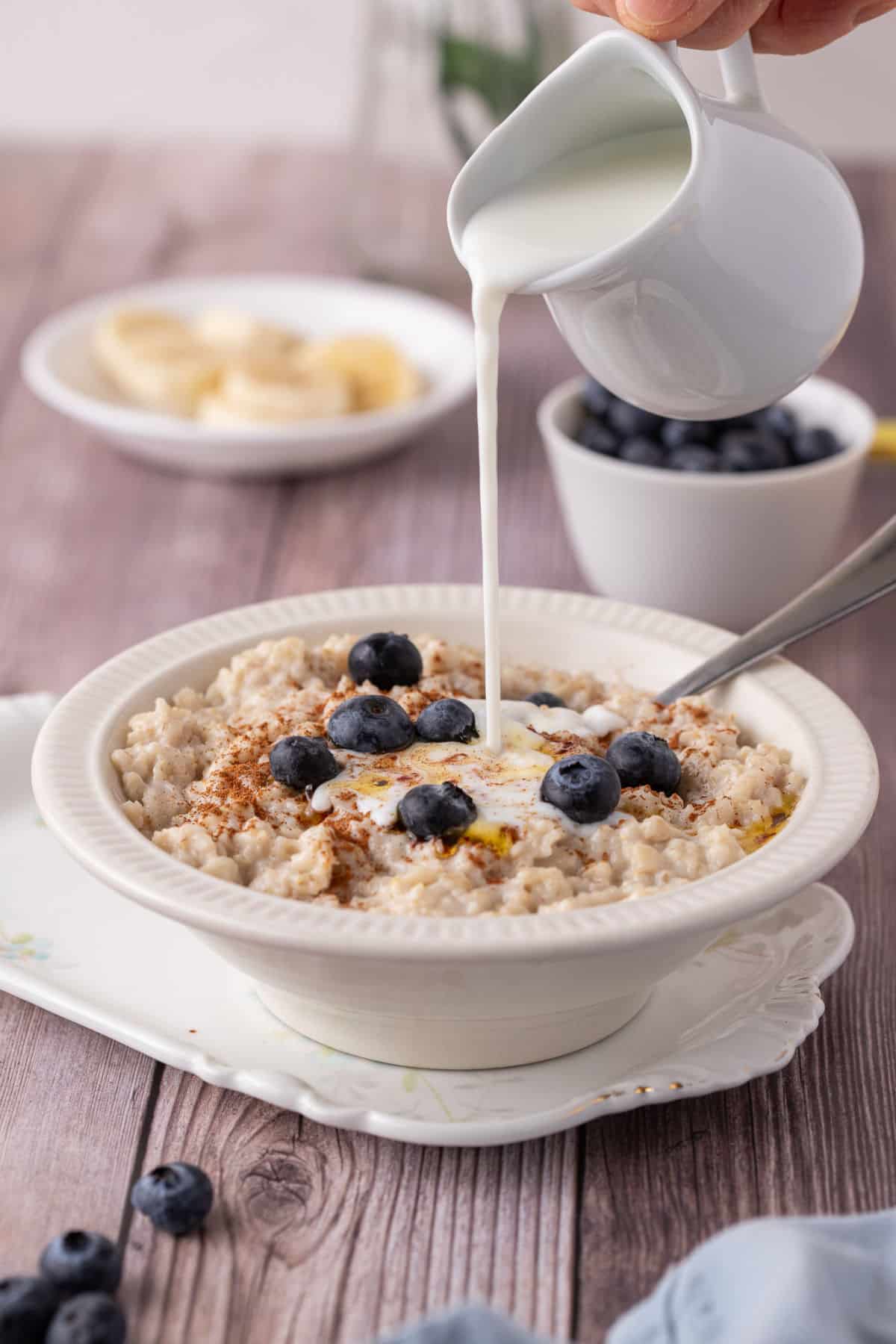 Pouring milk over a bowl of oatmeal.