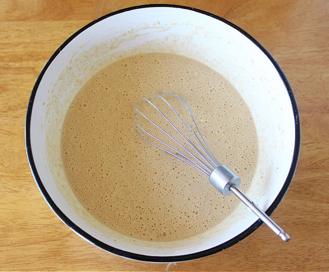 Waffle batter being whisked together in a large bowl.