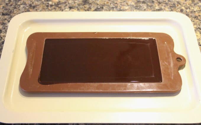Chocolate mold filled with chocolate 'batter' on a tan tray.