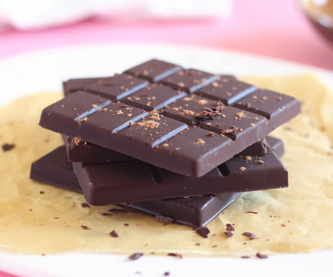 Stack of four chocolate bars with chocolate pieces sprinkled around.