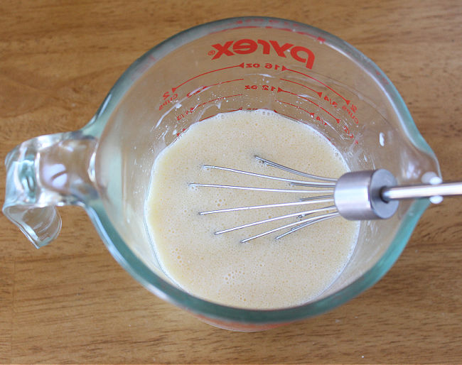 Whisking milk and egg in a small glass pitcher.