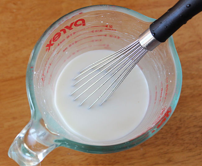 Whisking milk in a glass pitcher.