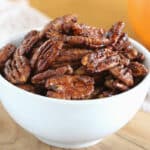 Glazed pecans in a white bowl.