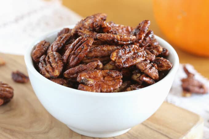 Glazed pecans in a white bowl.