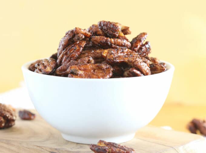 Heaped bowl of pecans on a wood cutting board.