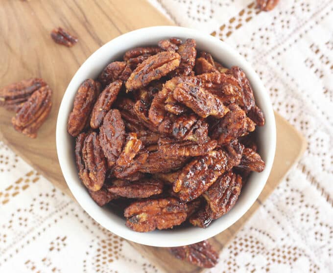 Overhead view of candied pecans in a white bowl.