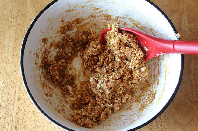 Cookie dough in a large white bowl with a red spoon stirring.