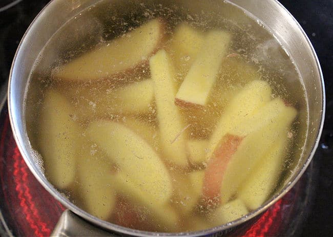 Boiling potato wedges in a large pot.