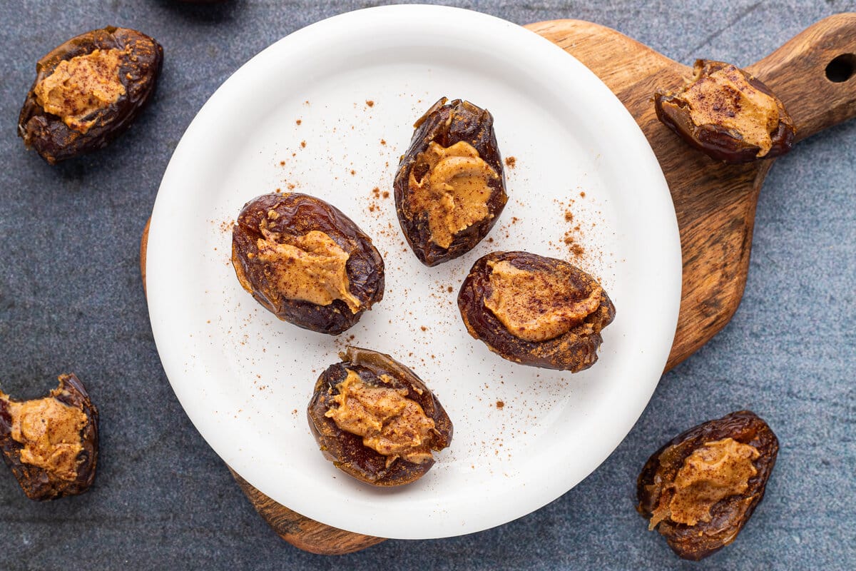 Four dates with peanut butter on a plate.