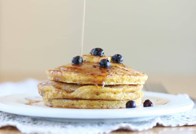 Stack of pancakes with syrup being poured on top.