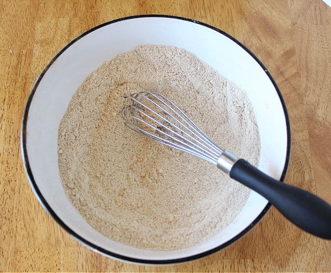 Whisking flour and baking soda in a white bowl.
