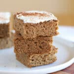 Stack of cake bars with frosting on a white plate.