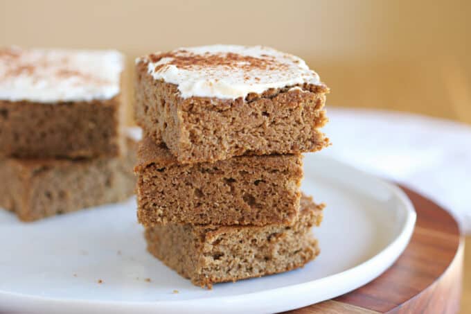 Stack of cake bars with frosting on a white plate.