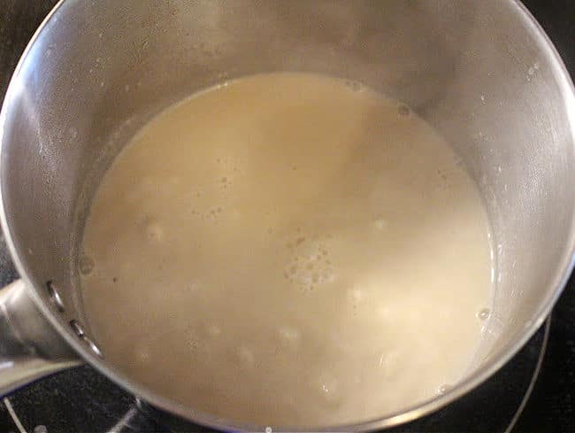 Milk boiling in a steel saucepan.